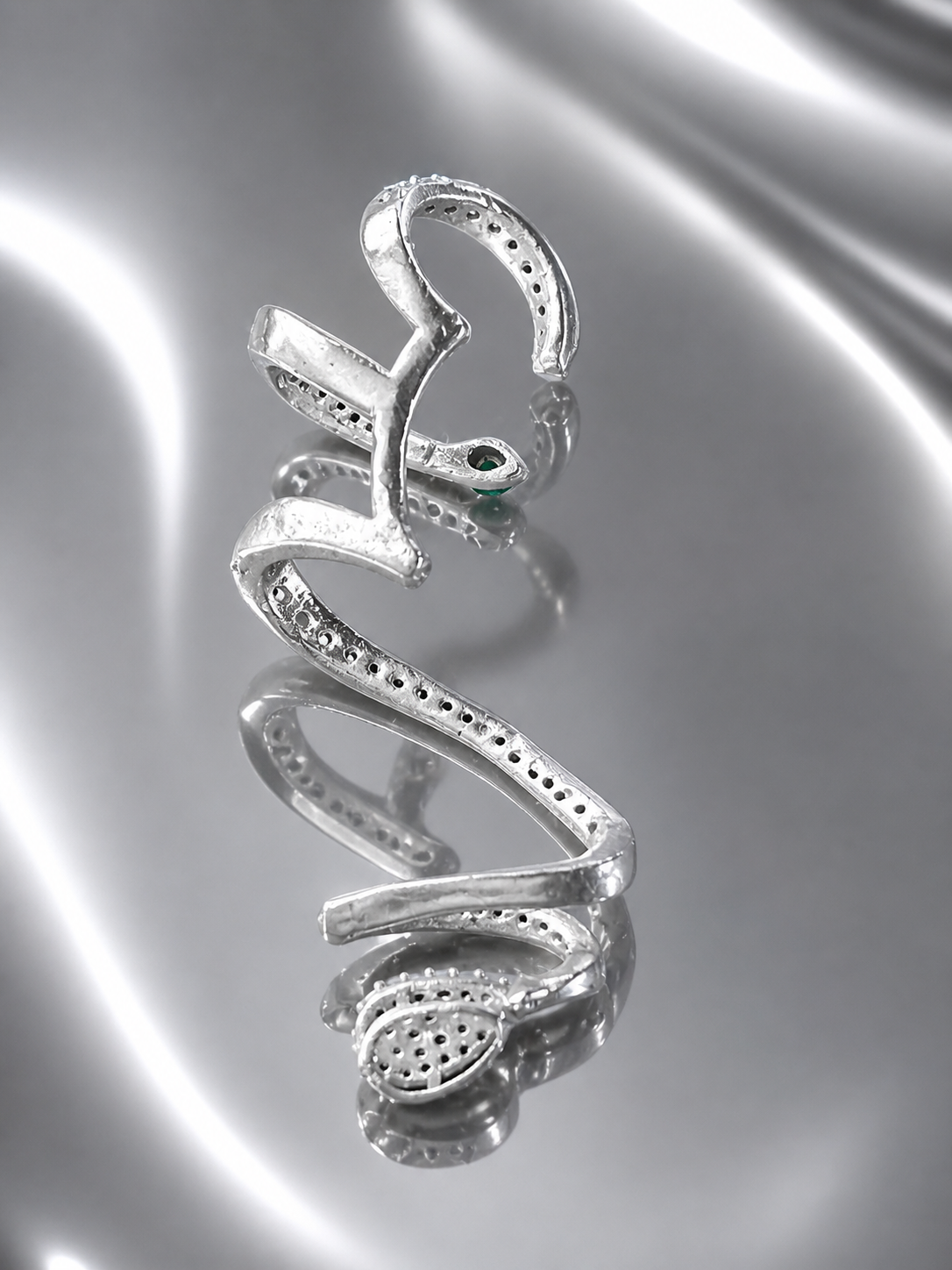 Near Earth Object | Silver snake-shaped pendant on a reflective silver surface