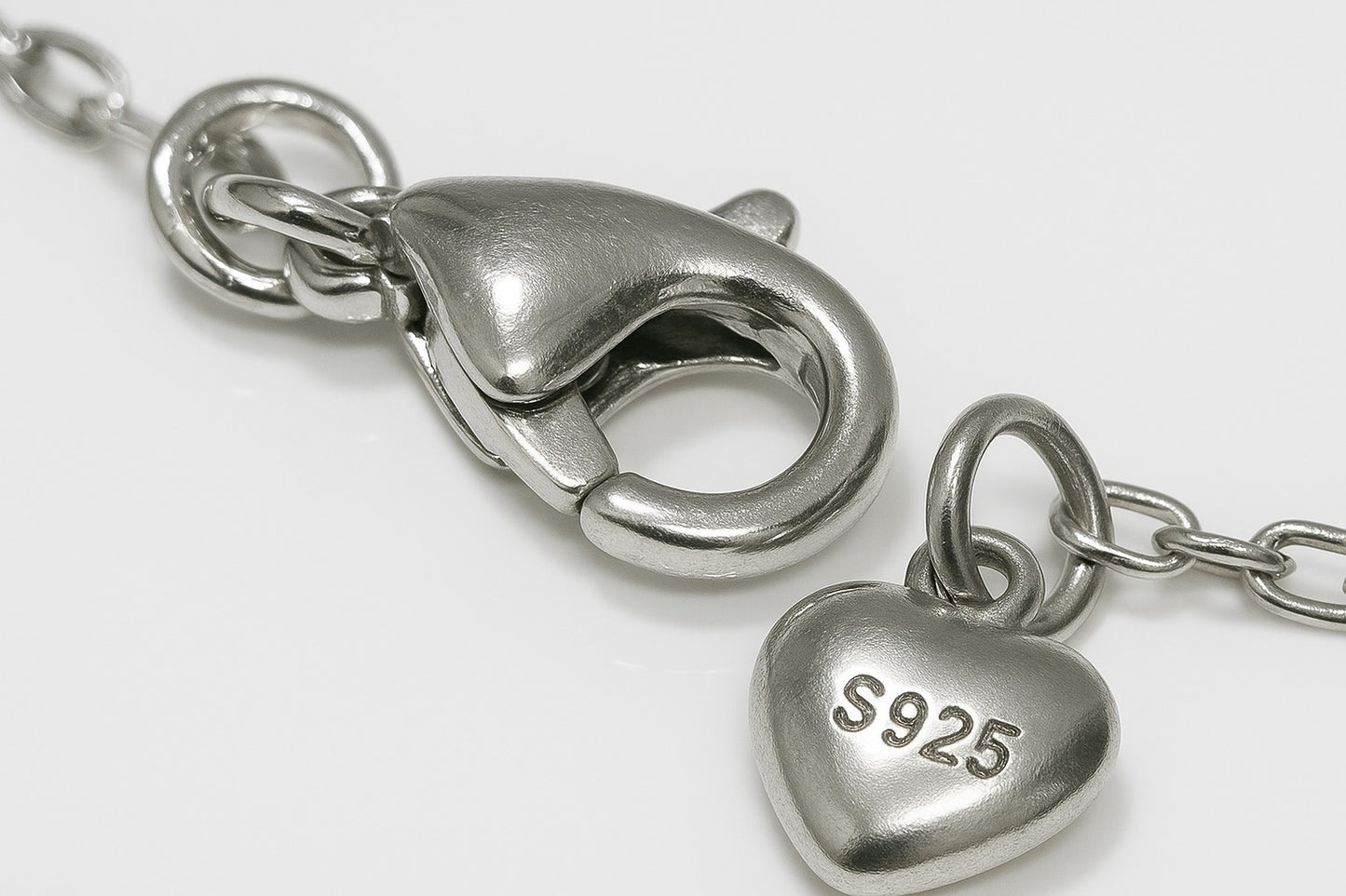 Silver necklace clasp detail with engraved charm tag – premium micro-bead bracelet by Near Earth Object.