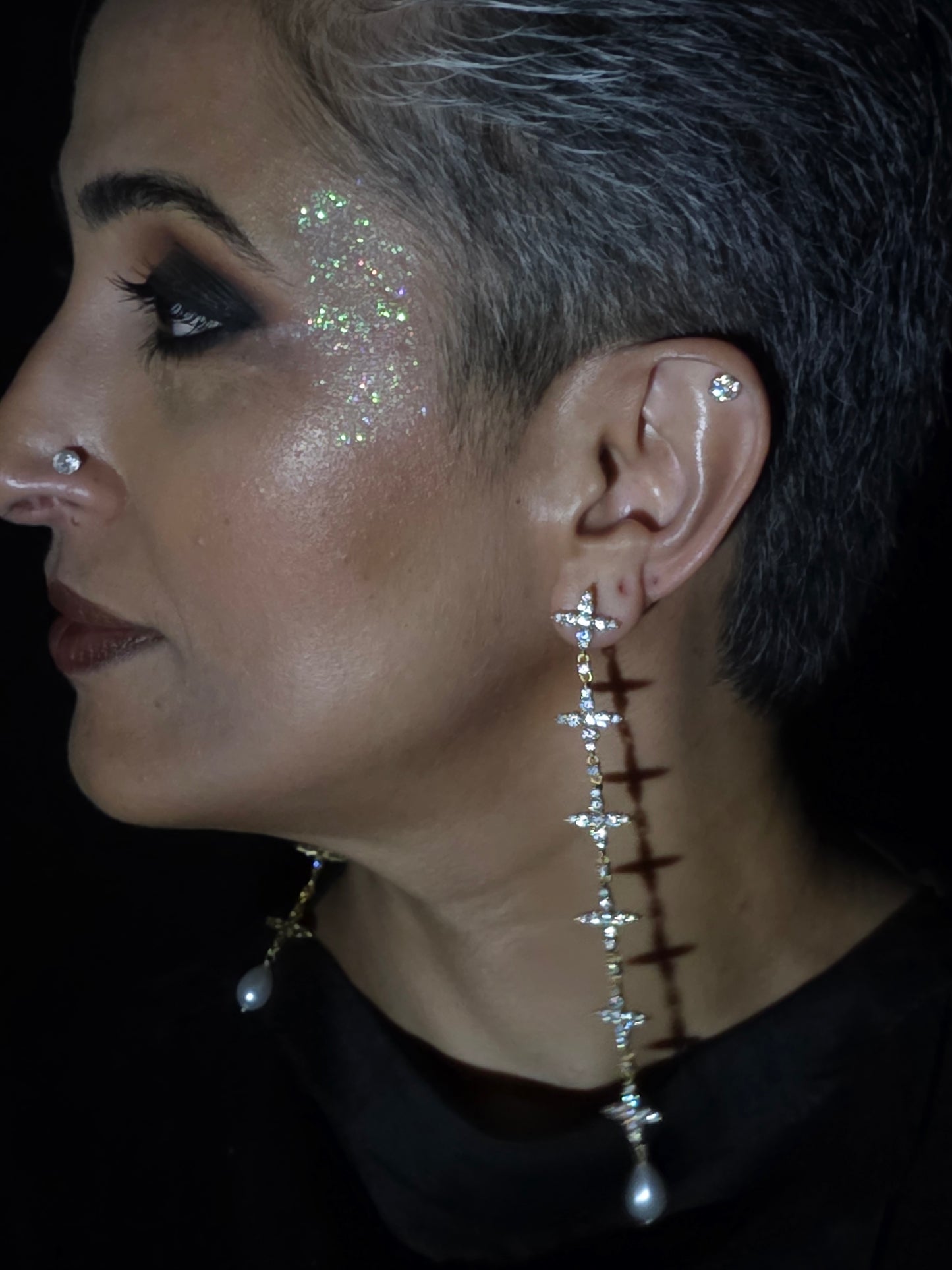 Near Earth Object | Close-up of a person wearing a decorative earring with small stones.