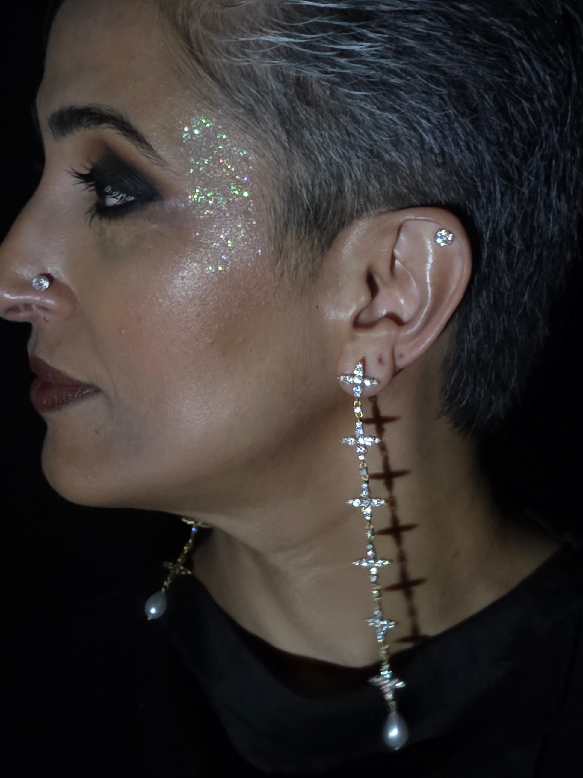 Near Earth Object | Close-up of a person wearing a decorative earring with small stones.