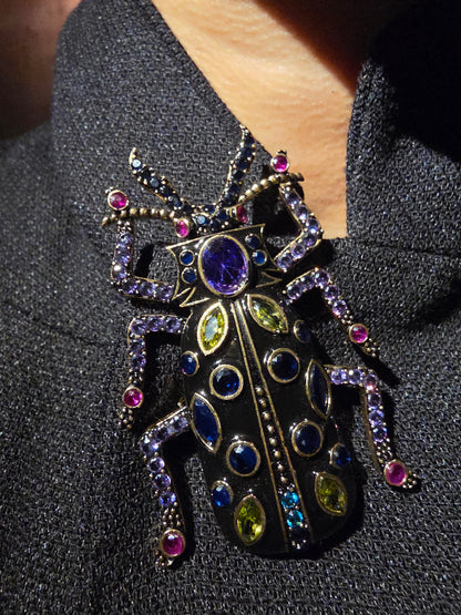 Near Earth Object | Decorative brooch with colorful gemstones on a textured surface