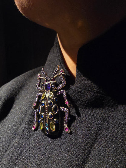 Near Earth Object | Decorative brooch with gemstones on a dark fabric background