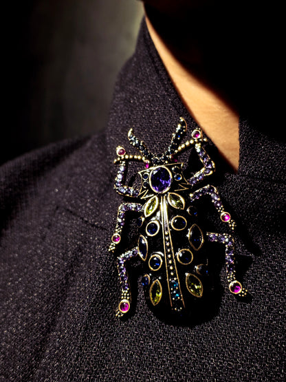 Near Earth Object | Elaborate Beetle-shaped brooch with gemstones on a dark fabric background
