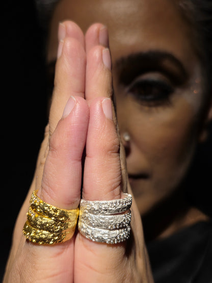 Near Earth Object | Close-up of a hand wearing two rings, one gold and one silver, with a blurred background.