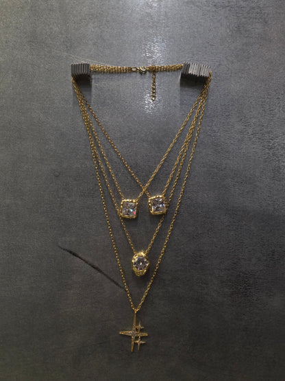 Near Earth Object | Gold necklace with diamond pendants on a dark gray background