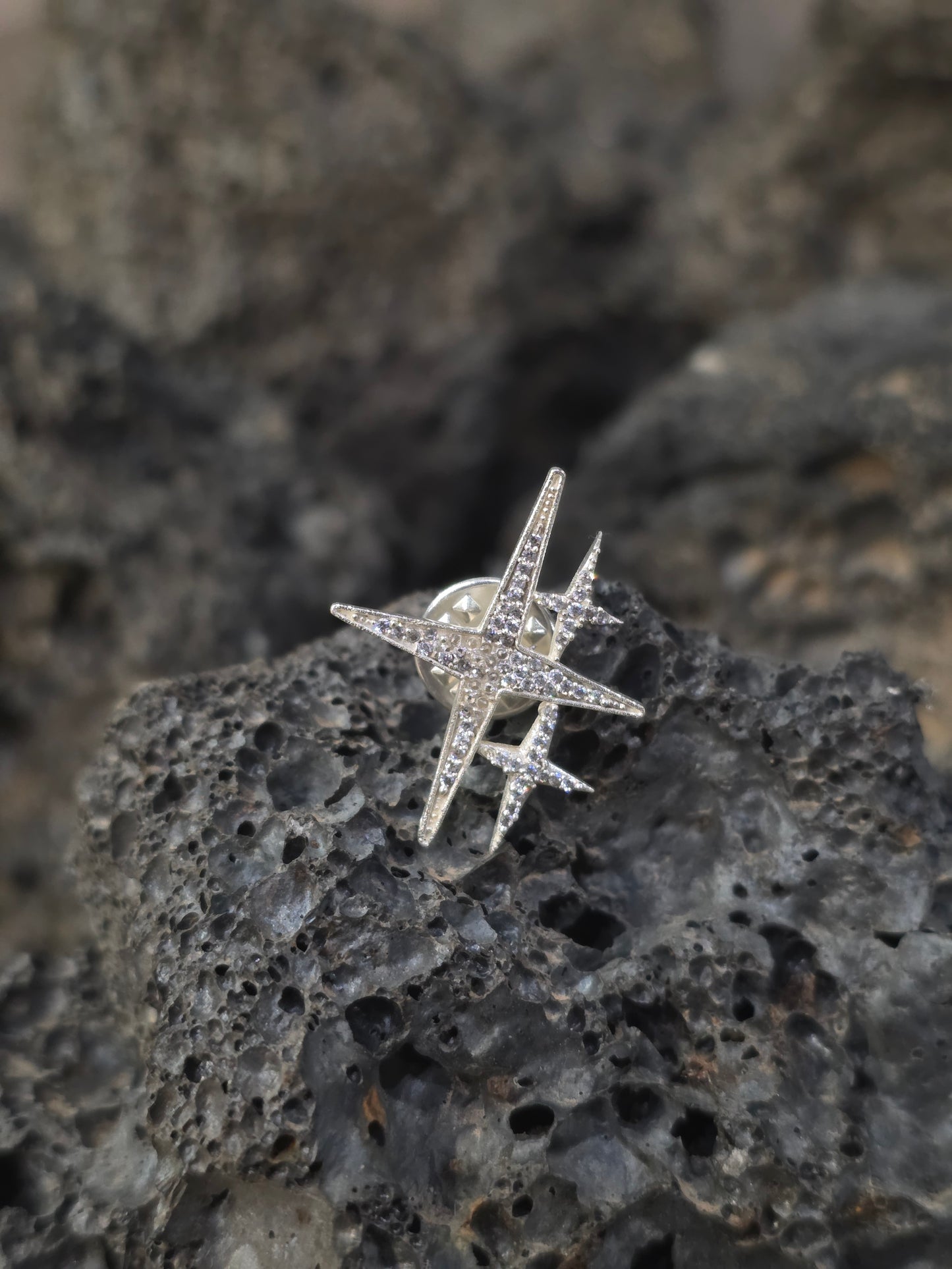 Near Earth Object | Star-shaped silver ring with gemstones on a textured stone surface