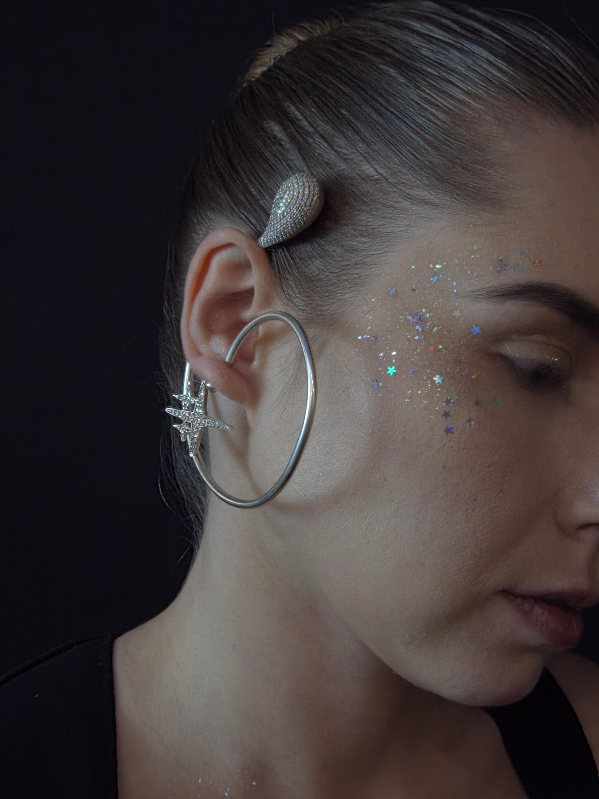 Near Earth Object | Close-up of a person wearing a silver earring with a star design.