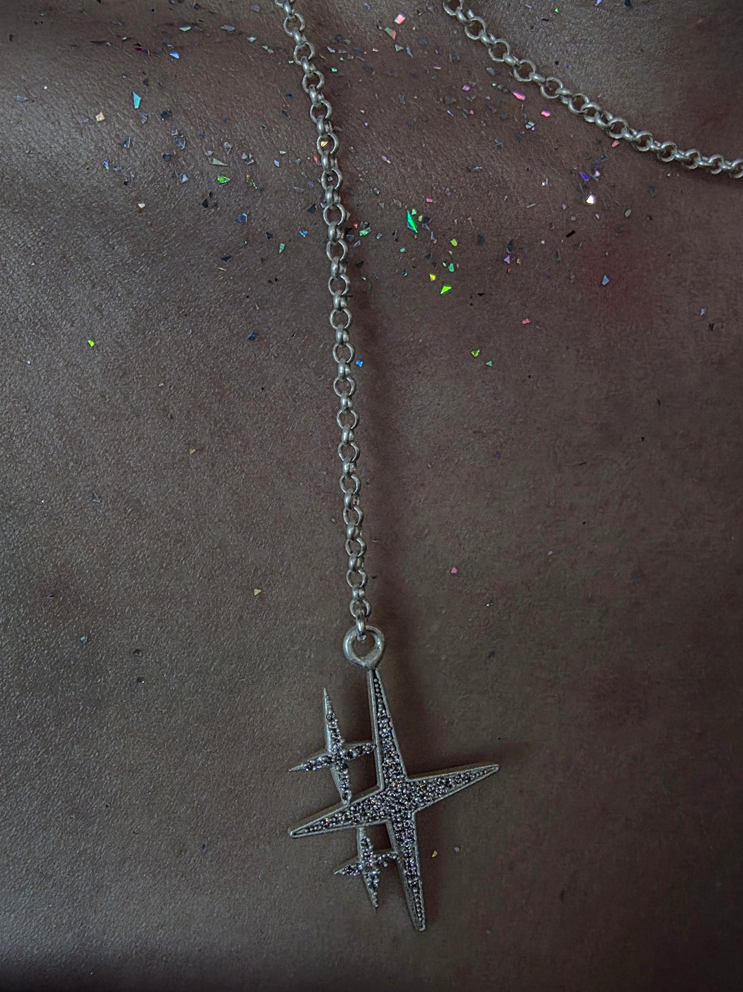 Near Earth Object | Silver necklace with a star-shaped pendant on a dark surface