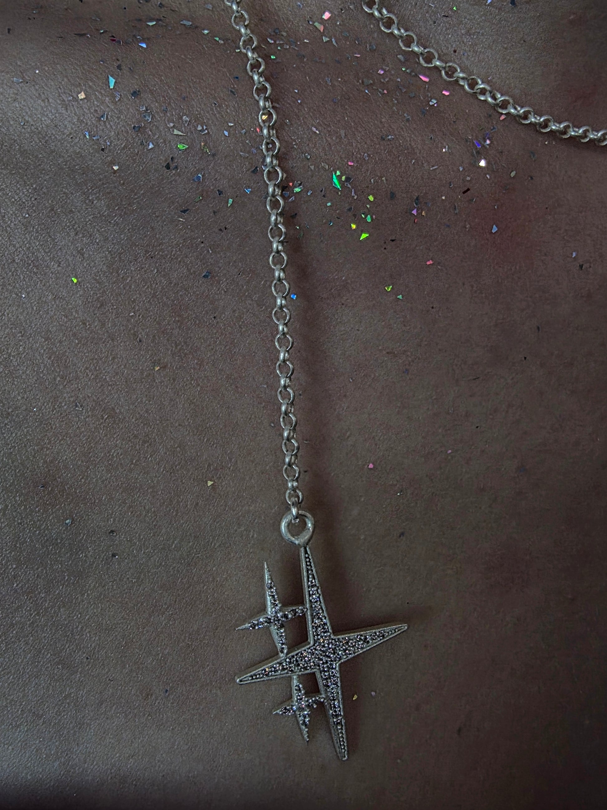 Near Earth Object | Silver necklace with a star-shaped pendant on a dark surface