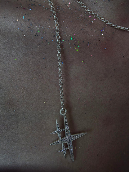 Near Earth Object | Silver necklace with a star-shaped pendant on a dark surface