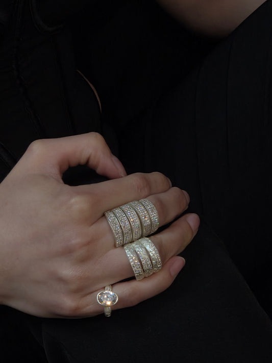 Close-up of Near Earth Object Nova Stack Ring – five open parallel silver bands each fully encrusted with rows of small pavé white crystals, worn together as one wide statement ring on the middle finger