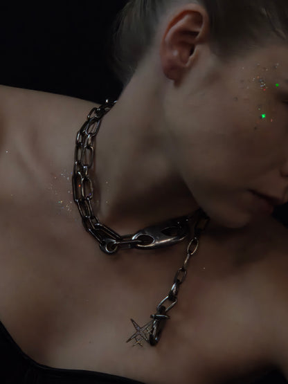 Near Earth Object | Close-up of a person wearing a chain necklace with a dark background