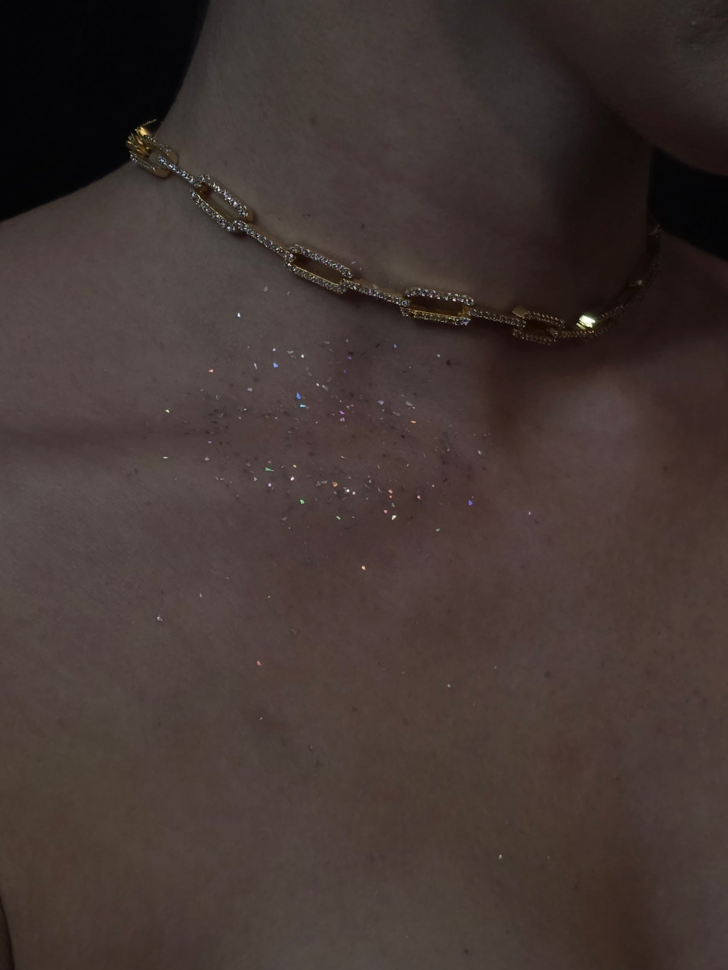 Near Earth Object | Close-up of a gold chain bracelet on a wrist with a dark background