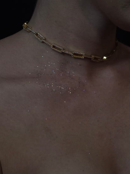 Near Earth Object | Close-up of a gold chain bracelet on a wrist with a dark background