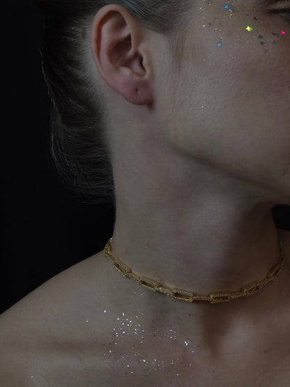 Near Earth Object | Close-up of an ear with a gold earring and colorful glitter on skin