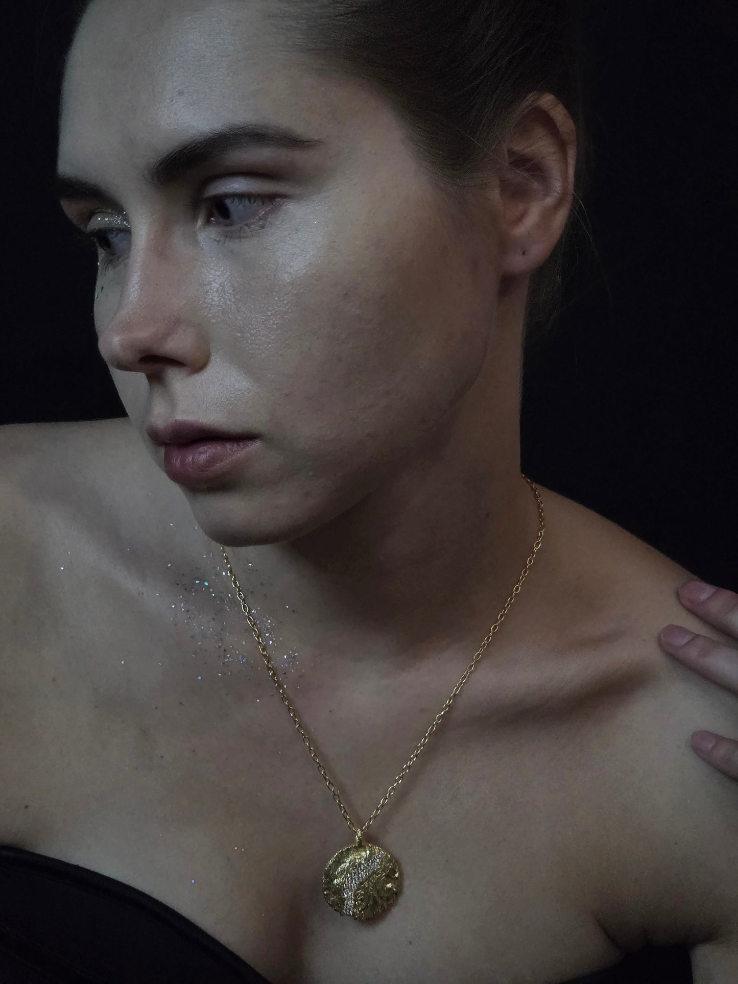 Near Earth Object | Close-up of a person wearing a gold necklace with a pendant.