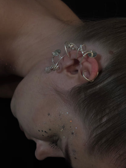 Near Earth Object | Close-up of an ear with a silver earring against a dark background