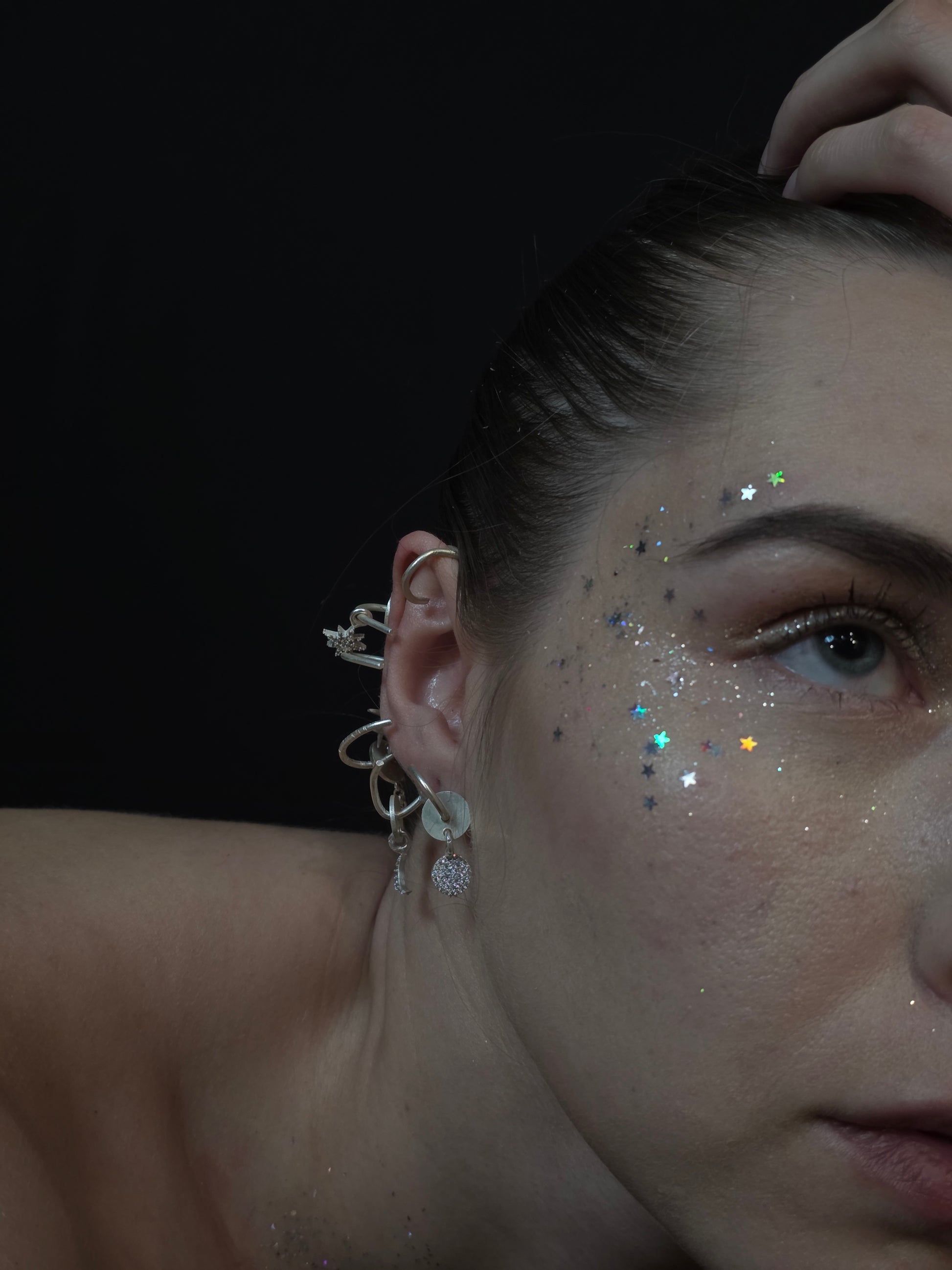 Near Earth Object | Close-up of a person's ear with a detailed earring against a dark background