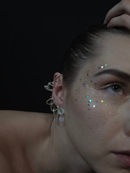Near Earth Object | Close-up of a person's ear with a detailed earring against a dark background