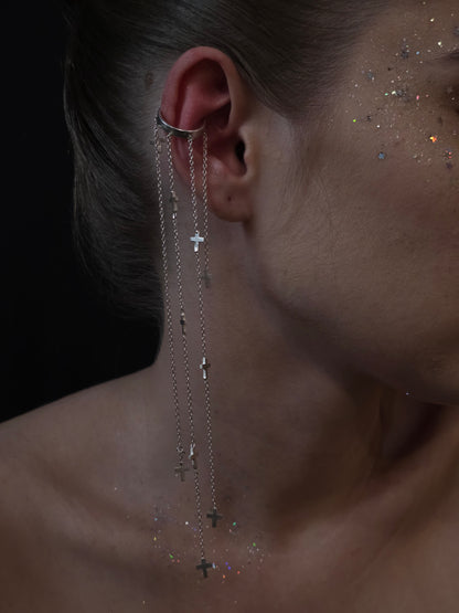 Near Earth Object Cross Cascade Cuff – statement silver ear cuff with cascading multi-chain drops and scattered mini cross pendants, styled on model with glitter makeup