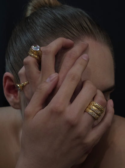 Near Earth Object | Close-up of a person wearing multiple gold rings with a dark background