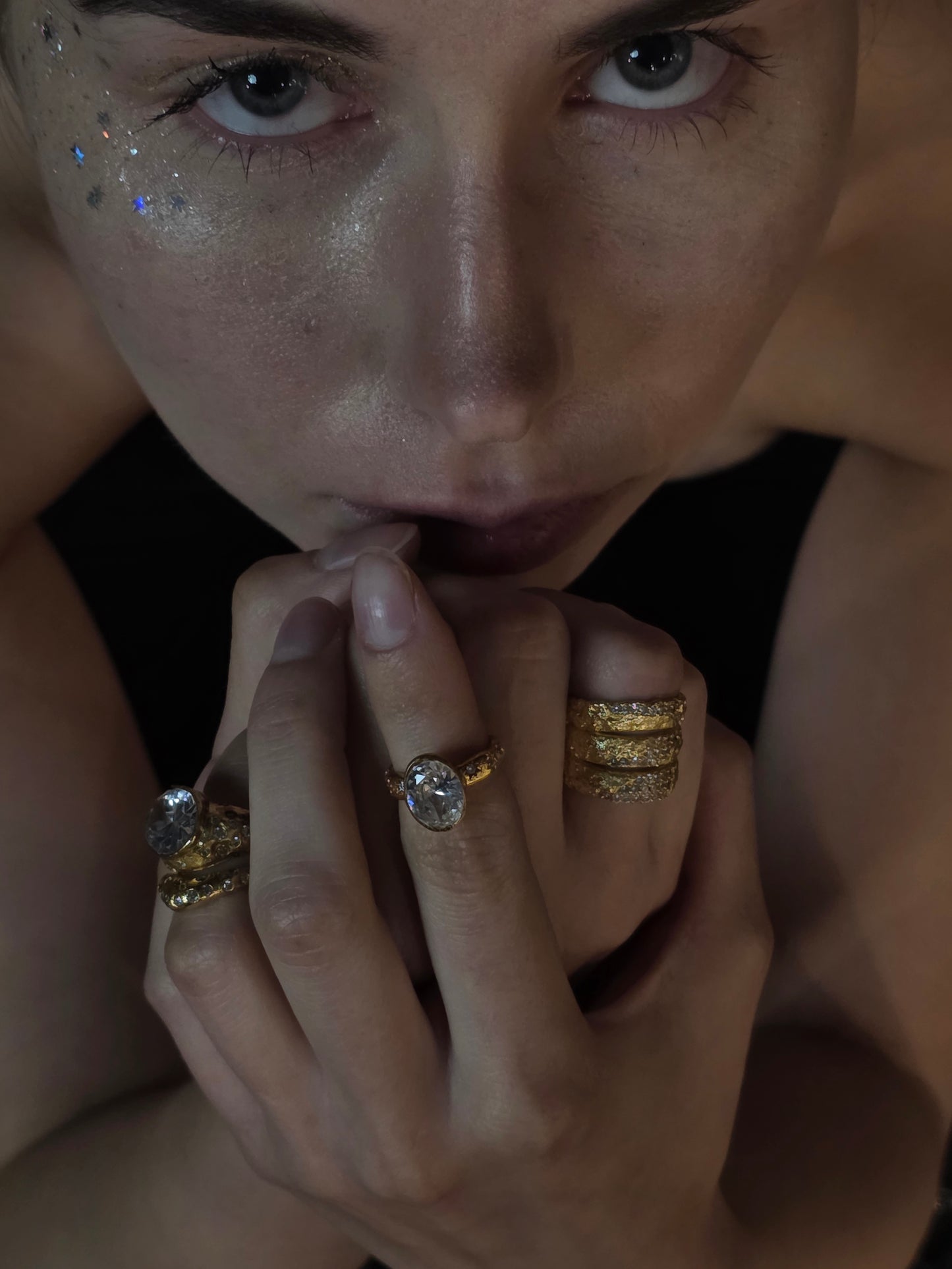 Near Earth Object | Close-up of a person wearing multiple gold rings with gemstones.