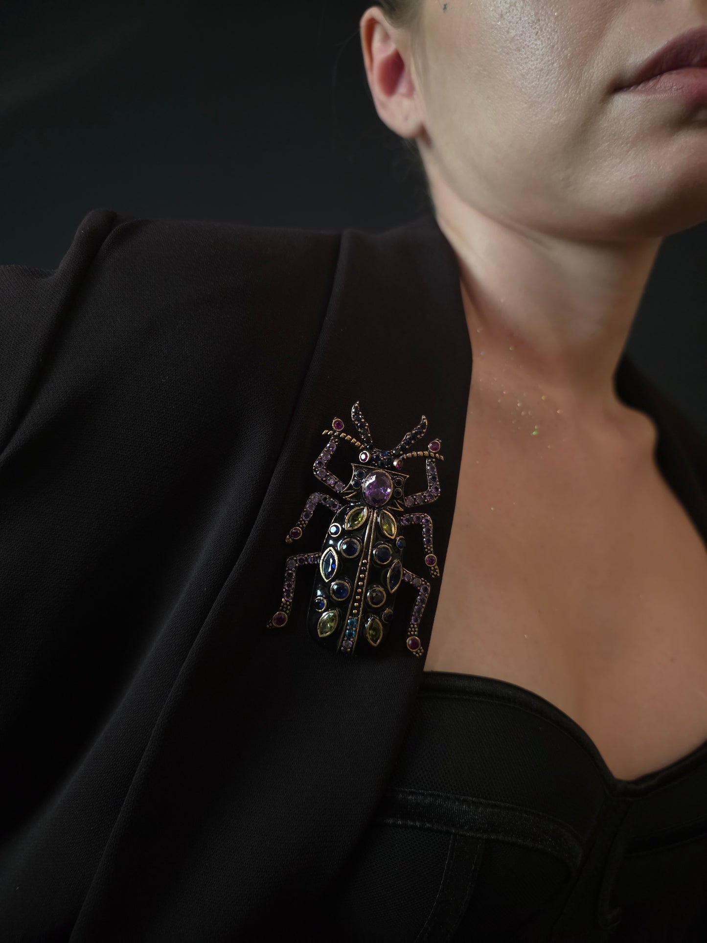 Near Earth Object | Close-up of a black garment with decorative brooches on a dark background