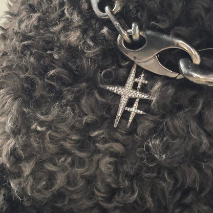 Near Earth Object | -shaped charm on a chain against a textured dark background