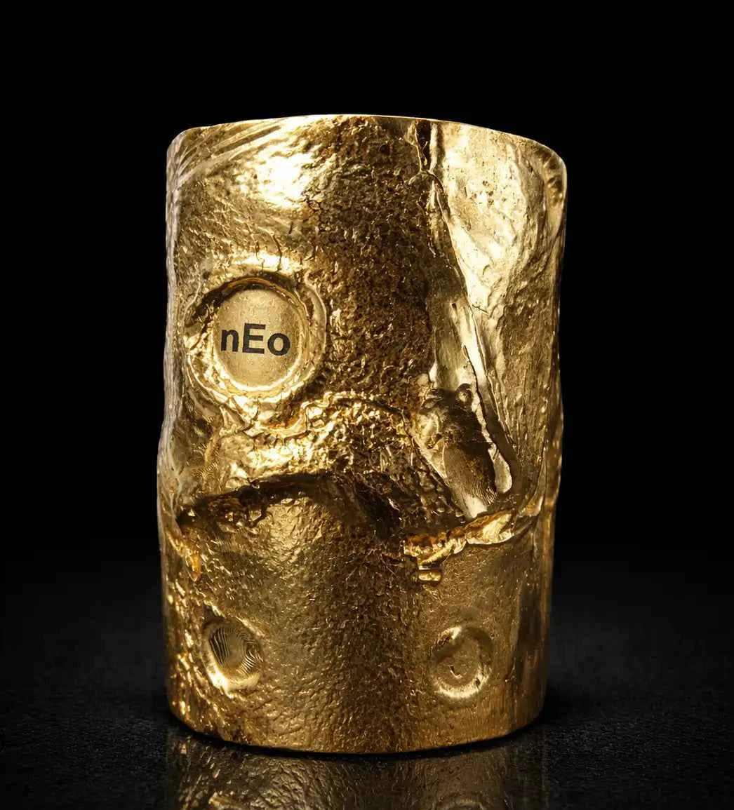 Gold-colored object with 'nEo' branding on a black background
