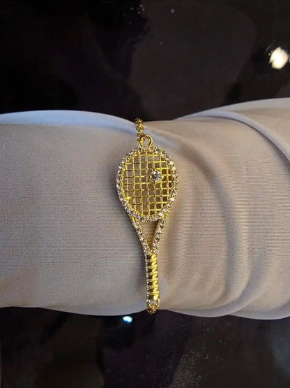 Gold bracelet shaped like a tennis racket on a wrist 