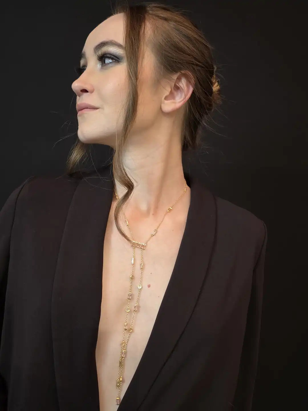Woman wearing a black blazer with a deep neckline, revealing a gold necklace 