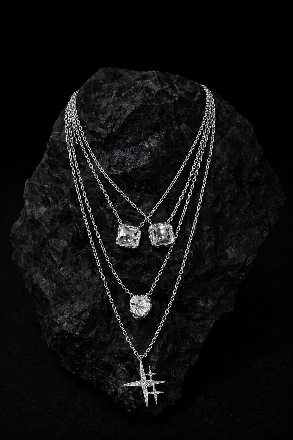 Near Earth Object | Three silver necklaces with gemstones on a textured black surface