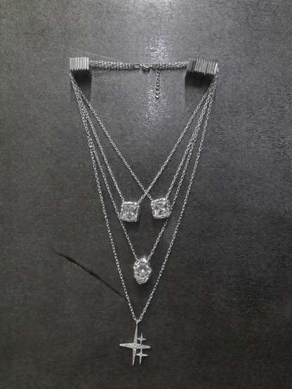Near Earth Object | Three silver necklaces with various pendants on a dark surface
