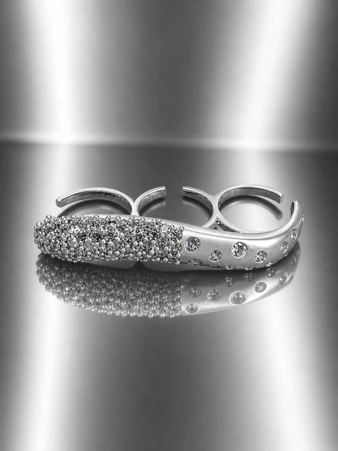 Near Earth Object | Silver knuckle ring with embedded stones on a reflective surface