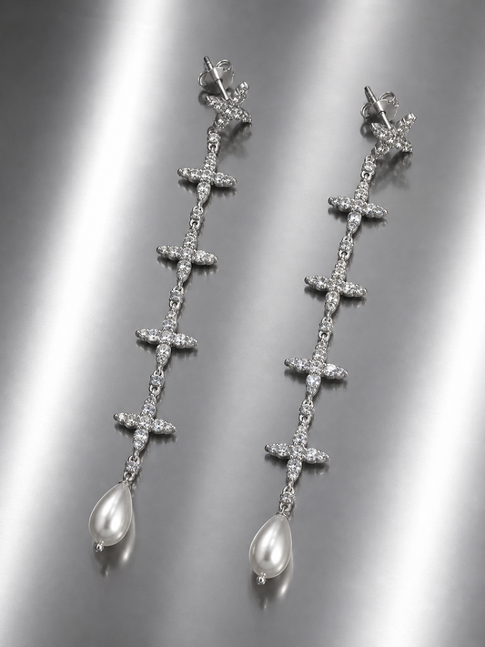 Near Earth Object | Silver cross-shaped earrings with pearl drops on a reflective surface