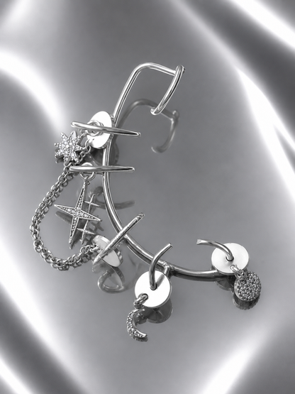 Near Earth Object | Silver earrings with various charms on a reflective surface