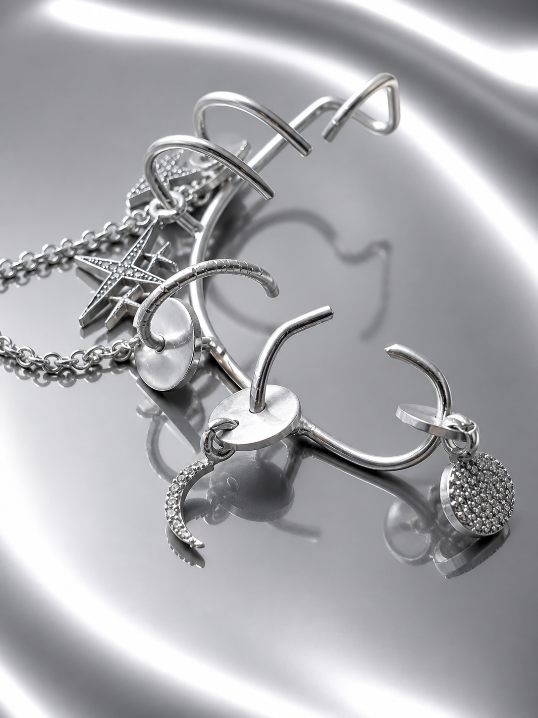 Near Earth Object | Silver jewelry set with charms on a reflective surface