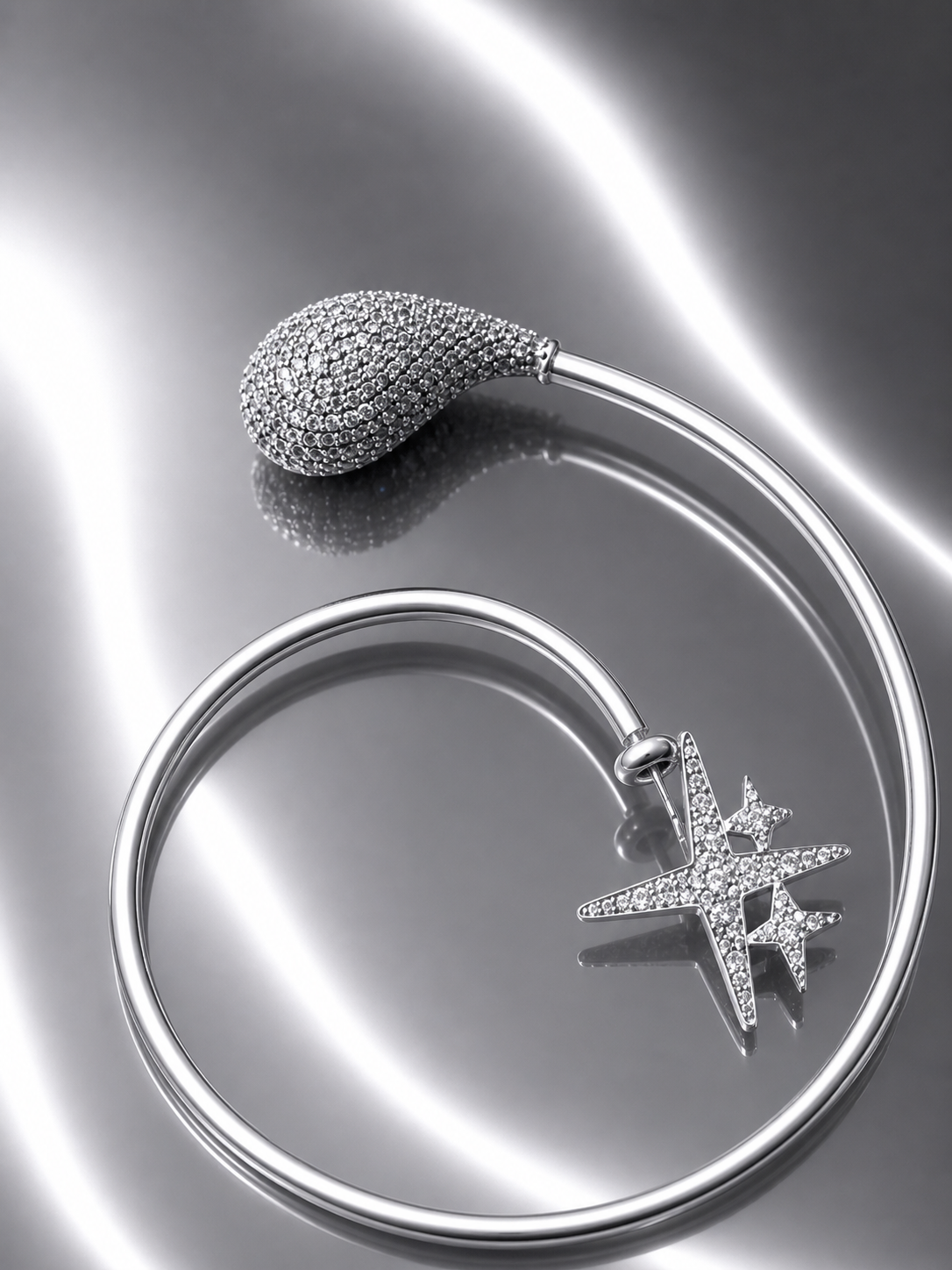 Near Earth Object | Silver jewelry piece with star design on a reflective surface