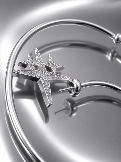 Near Earth Object | Silver star-shaped earring on a reflective surface