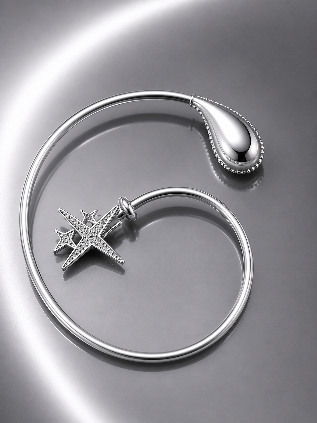 Near Earth Object | Silver bracelet with star-shaped charm on a reflective surface