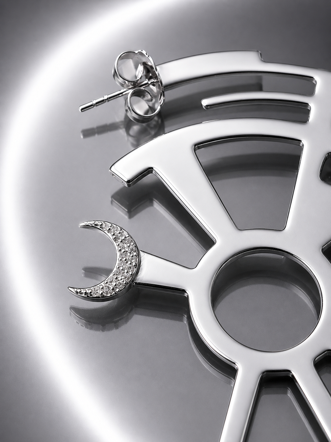 Near Earth Object | Silver earrings with moon design on a metallic surface
