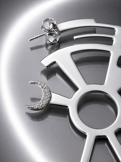 Near Earth Object | Silver earrings with moon design on a metallic surface
