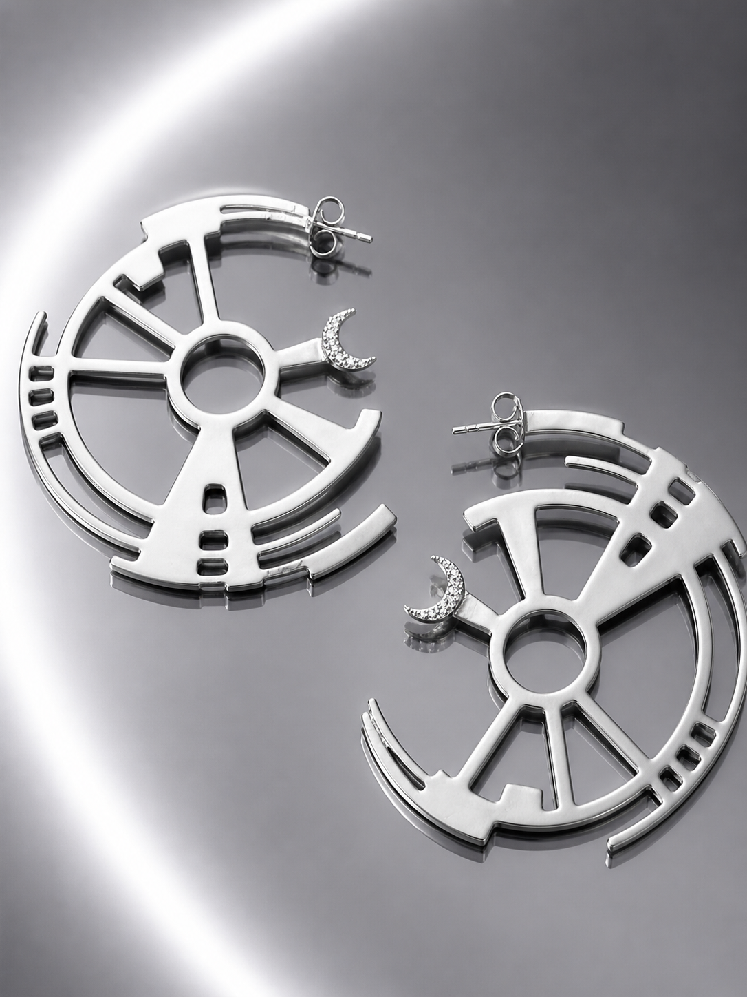 Near Earth Object | Pair of silver earrings on a reflective surface