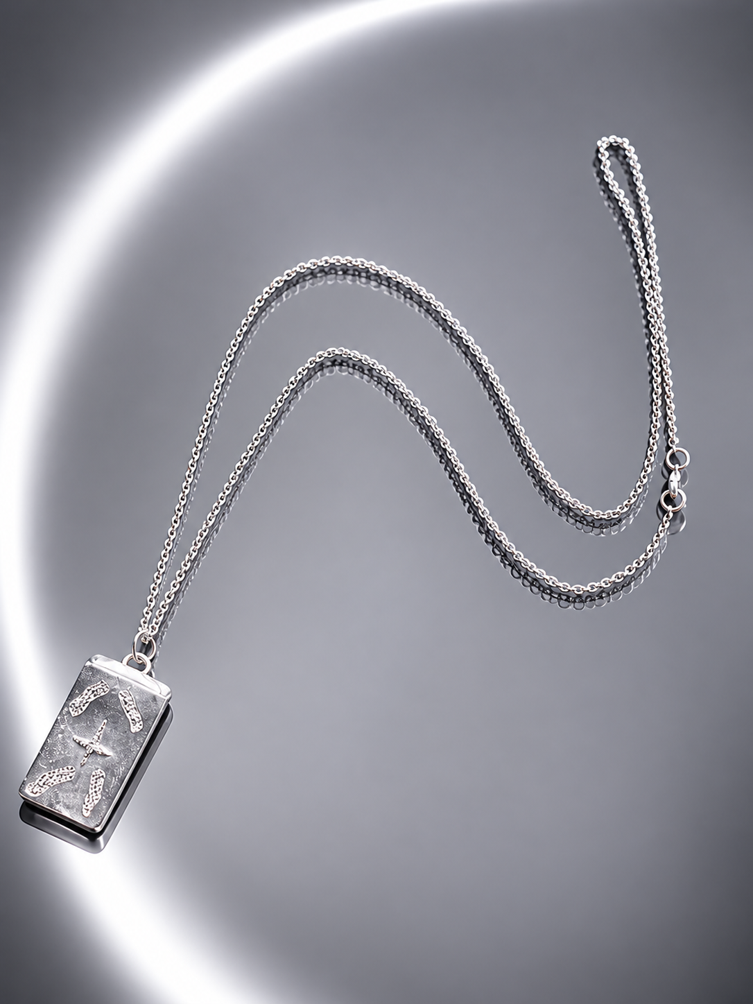 Near Earth Object | Silver necklace with a rectangular pendant on a reflective surface