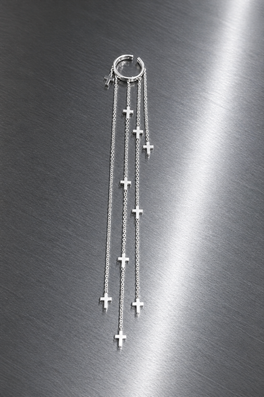 Silver cross necklace on a metallic surface