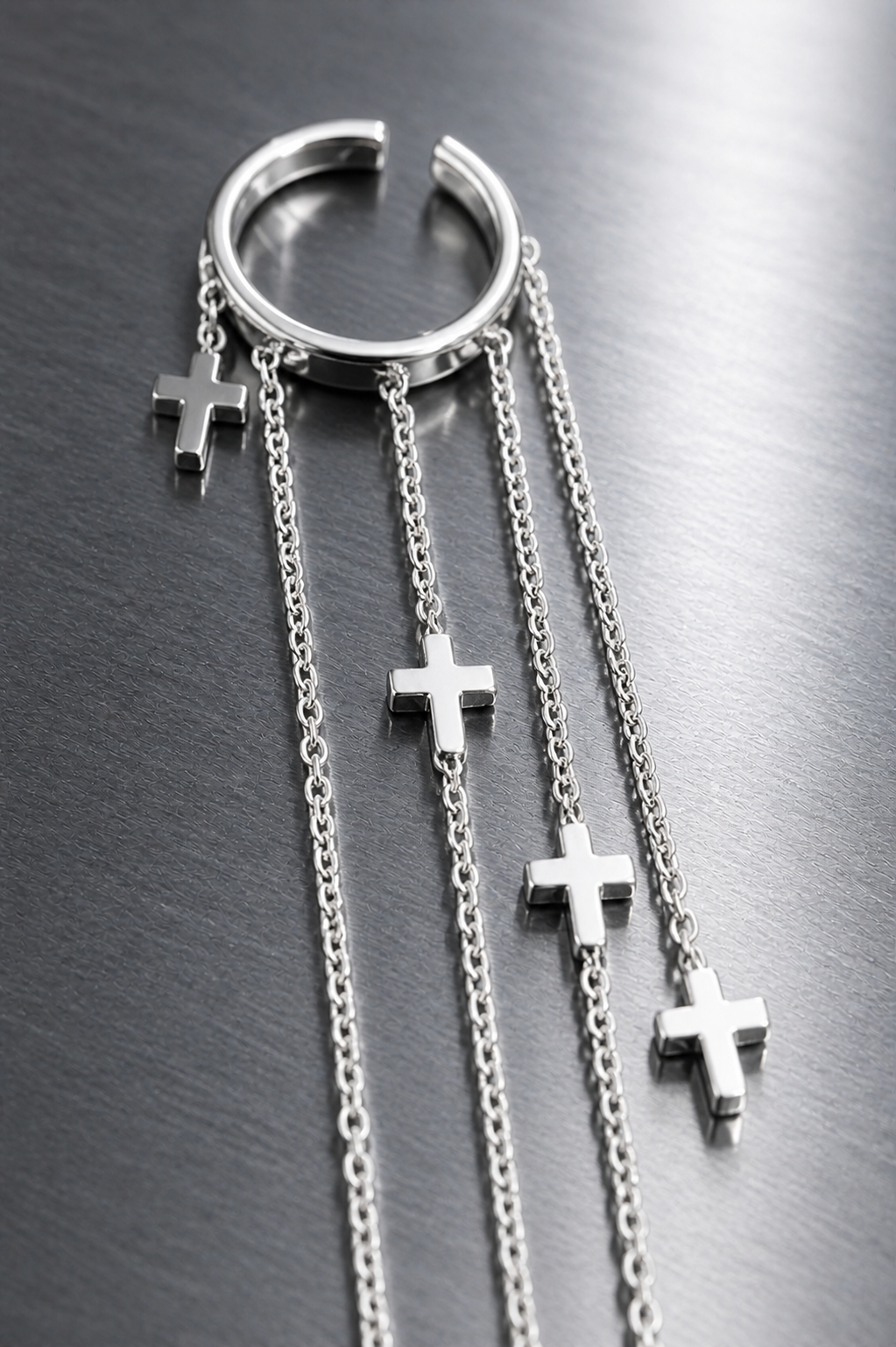 Silver hoop earring with cross charms on a metallic surface