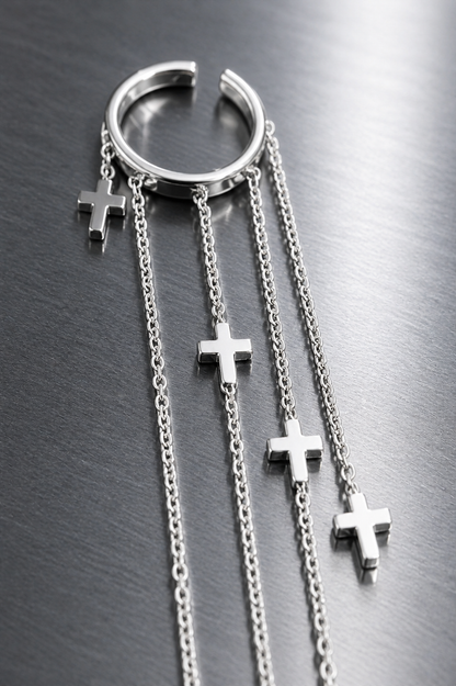 Silver hoop earring with cross charms on a metallic surface