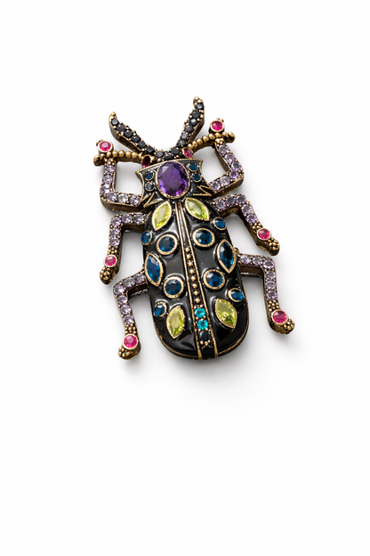 Near Earth Object | Decorative beetle-shaped brooch with multicolored gemstones on a white background