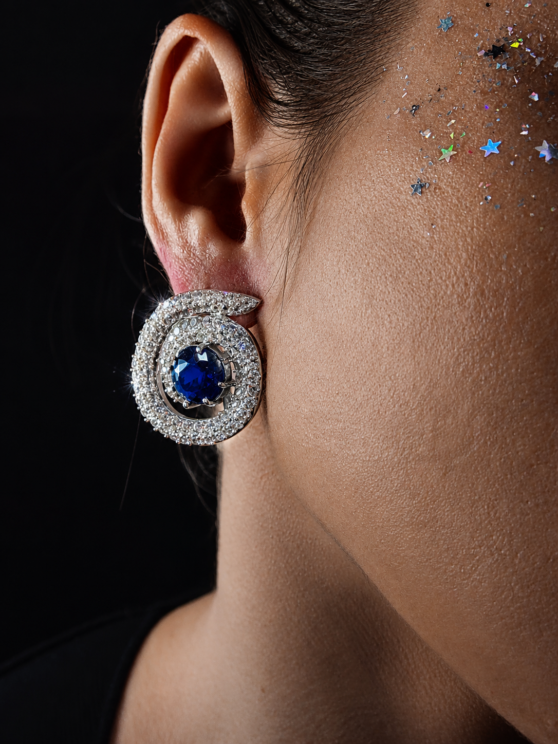 Near Earth Object | Close-up of an earring with a blue gemstone on a dark background