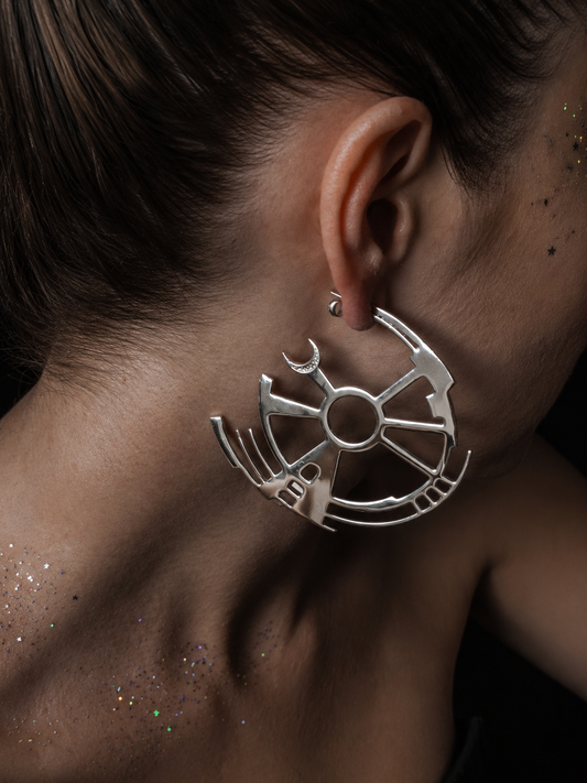 Near Earth Object | Close-up of a person wearing a silver earring with a geometric design.